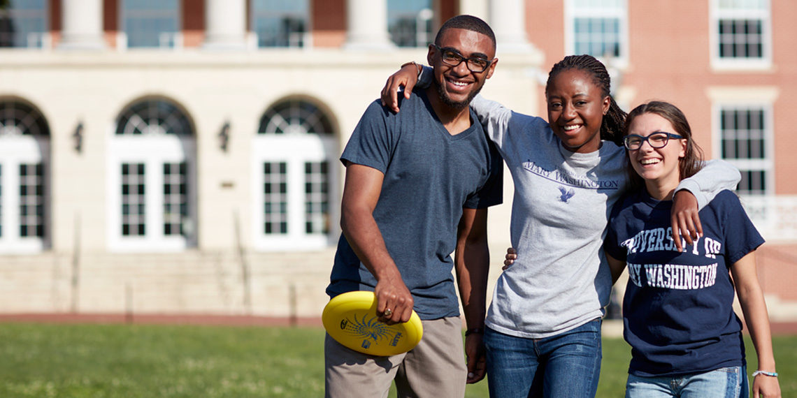Three students playing frisbee in front of the University Center