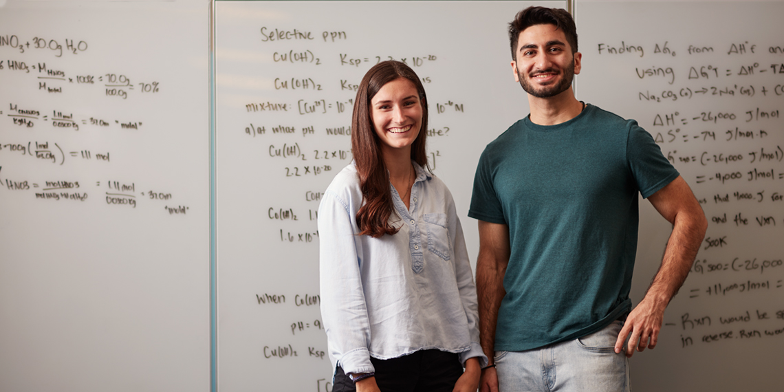 Students posing in front of a whiteboard with chemistry notes