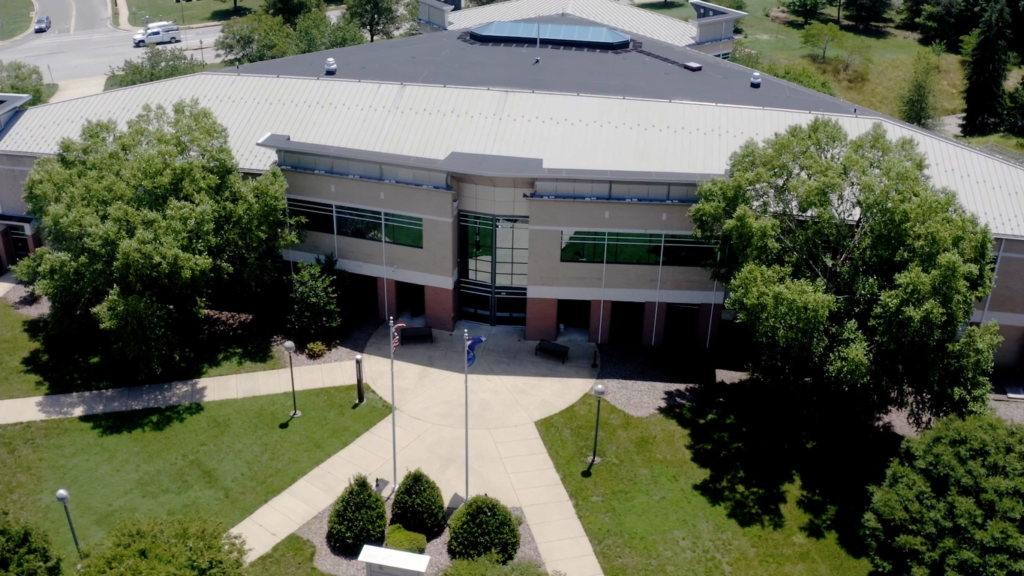 The image depicts an aerial view from a drone of a UMW building on a beautiful, transparent, warm summer day.