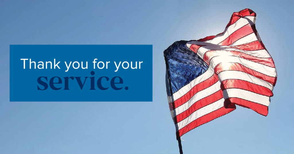 The image depicts the American flag highlighted by the shining sun, seen through the flag's transparency and waving in a soft wind on a clear blue-sky day. The text to the left of the flag states, "Thank you for your service."