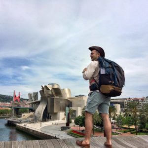 Student wearing a large backpack standing on a dock.