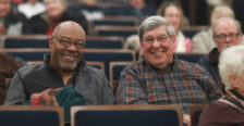 Two men sitting in the audience in Dodd Auditorium smiling at the camera.