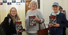 Three attendees holding the book titled, "A Mystery of Mysteries: The Death and Life of Edgar Allan Poe" by Mark Dawidziak.