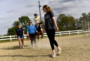UMW sophomores Elizabeth Finto (foreground) and Hannah Backe (in blue) volunteer on a recent Tuesday night with the therapeutic horseback riding program at Hazelwild Farm. Photo by Reza A. Marvashti.