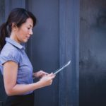 woman standing and looking down at a tablet