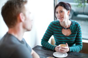 woman at table having a conversation with another person