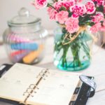 table with flowers in a vase, and a planner open.