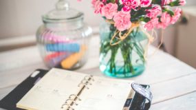 table with flowers in a vase, and a planner open.