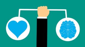 arm holding scale with heart on one side and a brain on the other.