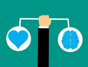 arm holding scale with heart on one side and a brain on the other.