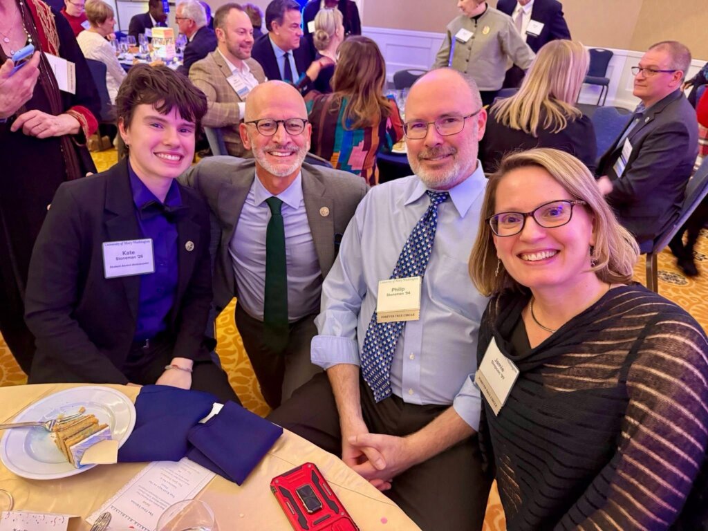 Student sits with President Paino and their parents in Chandler Ballroom at event. 