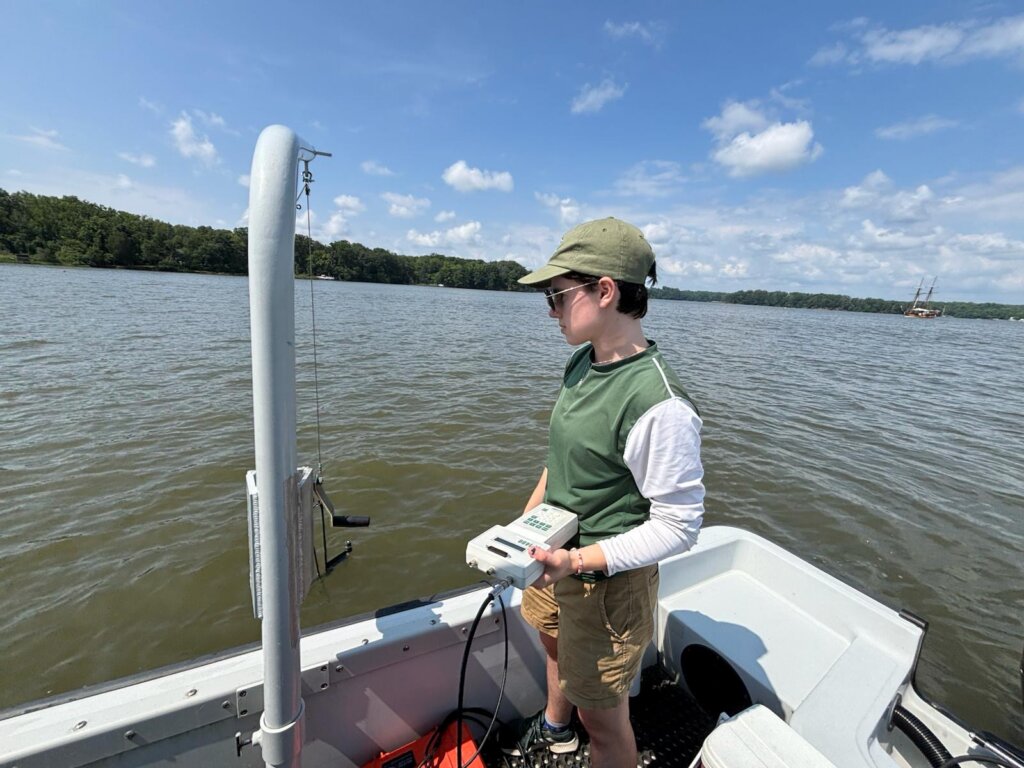 Student standing on a boat holding a li-cor while conducting research on the Chesapeake Bay. 