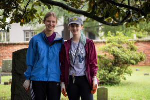 Sophomore Riley Anderson (left) and freshman Sarah Carlton clear ivy from the gravestones.