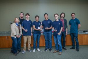 UMW students Collin Mistr, Diego Bustamante, Justin Rivera and Chad Baxter (middle four, from left to right) made up Team Devils at HackU 5, where they competed with groups from other schools to create programming solutions to university living. UMW alum Chris Halbert ’06, senior web engineer at Dominion Enterprises, which hosted the event, stands far right.