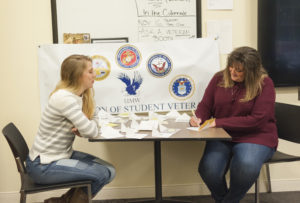 Student Michelle Justice, right, signs a thank-you card to a veteran as Jessica Roberson looks on.