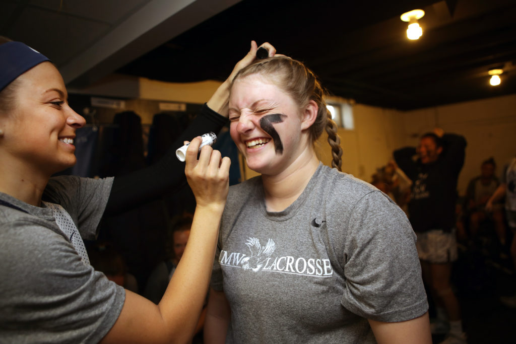 Senior Holly Hudson paints junior Shannon Bremer’s face in the locker room before the women’s lacrosse game. 