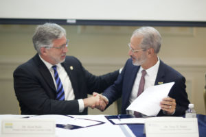 NOVA President Scott Ralls, left, and UMW President Troy Paino shake hands after signing the enhanced Guaranteed Transfer Partnership Agreement.