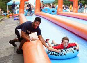 Sekai Walker (left) of UMW pushes a slider down the hill on the giant, 1,000-foot SlideFXBG. Photo by Suzanne Rossi.