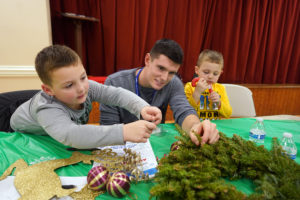 Senior Peyton Crickman helps Levi and Hunter Fishback decorate a holiday wreath.