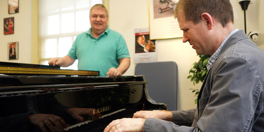 Brooks Kuykendall plays one of UMW's new Kawai pianos while Doug Gately looks on.