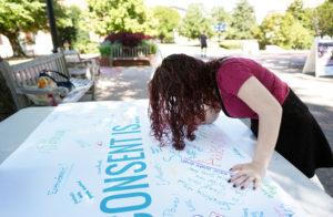 UMW sophomore Claudia Woods signs a Title IX banner at an event held earlier this semester. 