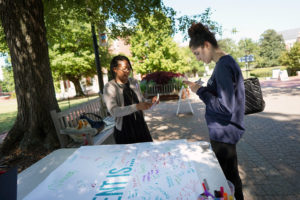 Associate Coordinator of Student Conduct Marissa Miller supports the Office of Title IX's table on Campus Walk as Sophia Eleni looks over information.