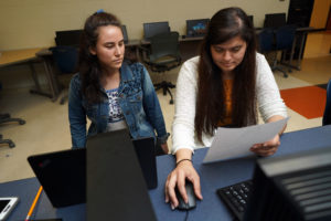 Natalie Florez (left) and Marlen Reyes (right), both UMW seniors, help tutor local teens at James Monroe High School in preparation for the GED test. Photo by Suzanne Rossi.