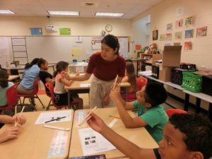 Japanese Outreach Coordinator Mina Uehara teaches 5th graders at Lafayette Upper Elementary school students how to use chopsticks.
