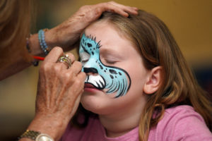 Kinzley Dougherty, 8, gets her face painted inside the University Center. Photo by Suzanne Carr Rossi.