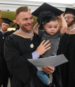 James Cooley tries on his father Brian Cooley's hat after the UMW Graduate School graduation ceremony.
