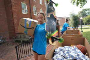 A volunteer carries a student's belongings to their residence hall. First-years brought everything from bedding, clothes and shower caddies, to skateboards, handmade quilts and sports equipment. Photo by Suzanne Rossi.