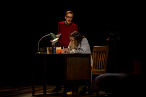 Playing Bechdel at age 43, Olivia Whicheloe (standing) observes her college-aged self, played by Lydia Hundley (seated). Both seniors, Whicheloe and Hundley are one of three actors playing graphic memoirist Alison Bechdel in 'Fun Home.' Photo by Geoff Greene.