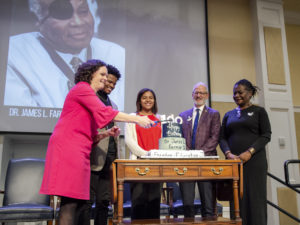 Vice President for Student Affairs Juliette Landphair lights the candle on Dr. Farmer's cake, while SGA President Jason Ford, Legacy Council Member Courtney Flowers, President Troy Paino and Vice President for Equity and Access Sabrina Johnson look on. Photo by Tom Rothenberg.