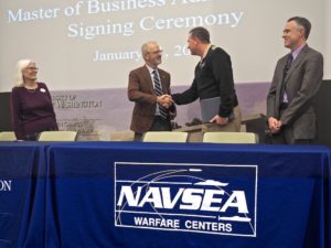 And a handshake makes it official. President Troy Paino and Capt. Casey Plew finalize the partnership after signing documents of agreement. To the left is UMW Provost Nina Mikhalevsky, and NSWCDD Acting Technical Director Darren Barnes is on the right. Photo by Robert A. Martin.