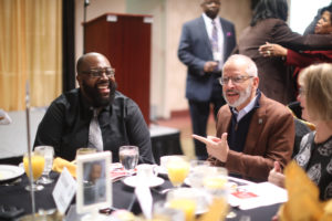 James Farmer Multicultural Center Assistant Director Chris Williams (left) talks with UMW President Troy Paino and wife Kelly at the Fredericksbrug NAACP Branch MLK Day Breakfast in January. Williams is advisor to UMW's new chapter of the NAACP, chartered last May. Photo by Karen Pearlman.