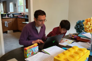 Kashef Majid, an associate professor in the College of Business, grades marketing papers in the workspace he shares with his son.
