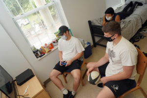 Rugby players Lloyd Stephens of England (with control), Wen Yates of Williamsburg (on bed) and Aidan Hendry of Scotland play video games and follow social-distancing guidelines during Mary Washington Move-In. Photo by Suzanne Rossi.