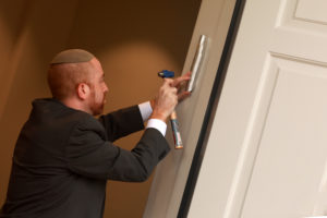 Rabbi Menachem Sherman, the Center director, hammers a mezuzah on the doorpost, which serves as a reminder that homes are holy places and those that enter should act accordingly. Photo by Karen Pearlman.