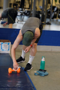 A student wipes down weights after using them in the UMW Fitness Center. Photo by Suzanne Carr Rossi.
