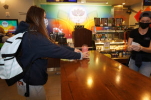 Donning a Mary Washington mask from the UMW bookstore, freshman Lexi St. Clair picks up a smoothie in Katora Cafe. Photo by Suzanne Carr Rossi.