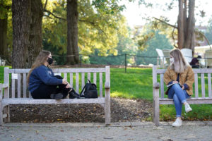 Bench-sitting looks a little bit different in the time of COVID-19, but UMW juniors Kira Frazee (left) and Allison Bliss find a way to enjoy the popular UMW pastime while seated separately. Photo by Suzanne Carr Rossi.