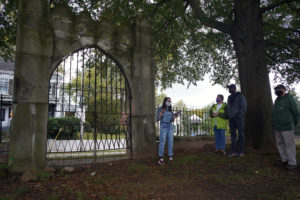 Freshman Eliza Vegas shows off the massive iron City Cemetery gate, constructed by local iron workers and stone masons. Photo by Suzanne Carr Rossi.