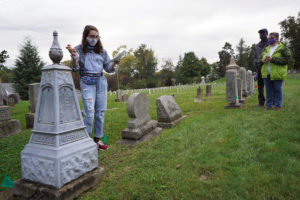 Freshman Eliza Vegas gives tour participants a crash course in Victorian-era funerary practices, which included use of these zinc or "white bronze" markers that were manufactured by the Monumental Bronze Company of Bridgeport, Connecticut from 1874 to 1914. Photo by Suzanne Carr Rossi.