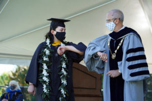 UMW President Troy Paino elbow bumps Gabi Radoiu '20 as she crosses the stage. Handshakes were out this year due to the pandemic. Photo by Suzanne Carr Rossi.