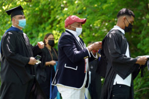 True to tradition, Dean of Students Cedric Rucker adjusts graduates' regalia during one of three Commencement ceremonies for the Class of 2020. Photo by Suzanne Carr Rossi.