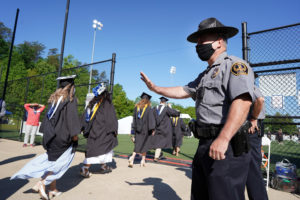 Campus Police Chief Mike Hall extends waves and well wishes to graduates as they process onto the Campus Recreation Field. All of his officers played key roles in the ceremonies. Photo by Suzanne Carr Rossi.