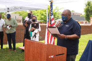 Chris Williams serving as emcee for today's ceremony unveiling the temporary historic marker, as Mayor Mary Katherine Greenlaw, Vice Mayor Chuck Frye and Delegate Joshua Cole look on. Photo by Karen Pearlman.