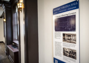 Historic preservation students helped create interpretive panels, like the one in the foreground, which are placed throughout Virginia Hall to commemorate the building's rich history. The lighted sconces in the background were among original features restored in the hall, which was built in three stages beginning in 1914. Photo by Tom Rothenberg.
