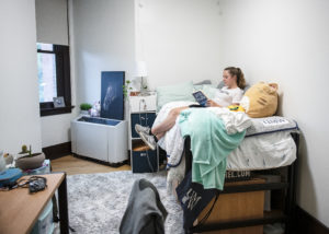 Sophomore psychology major Addie Sage, a resident assistant, reads in her room in Virginia Hall. The 168-bed residence hall will house first-year students. Photo by Tom Rothenberg.