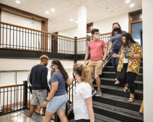 A group walks down one of the signature open stairways in Virginia Hall. The stone stairs and hardwood banisters were revived as part of a $19 million renovation to the building, whose construction began in 1914. Photo by Tom Rothenberg.